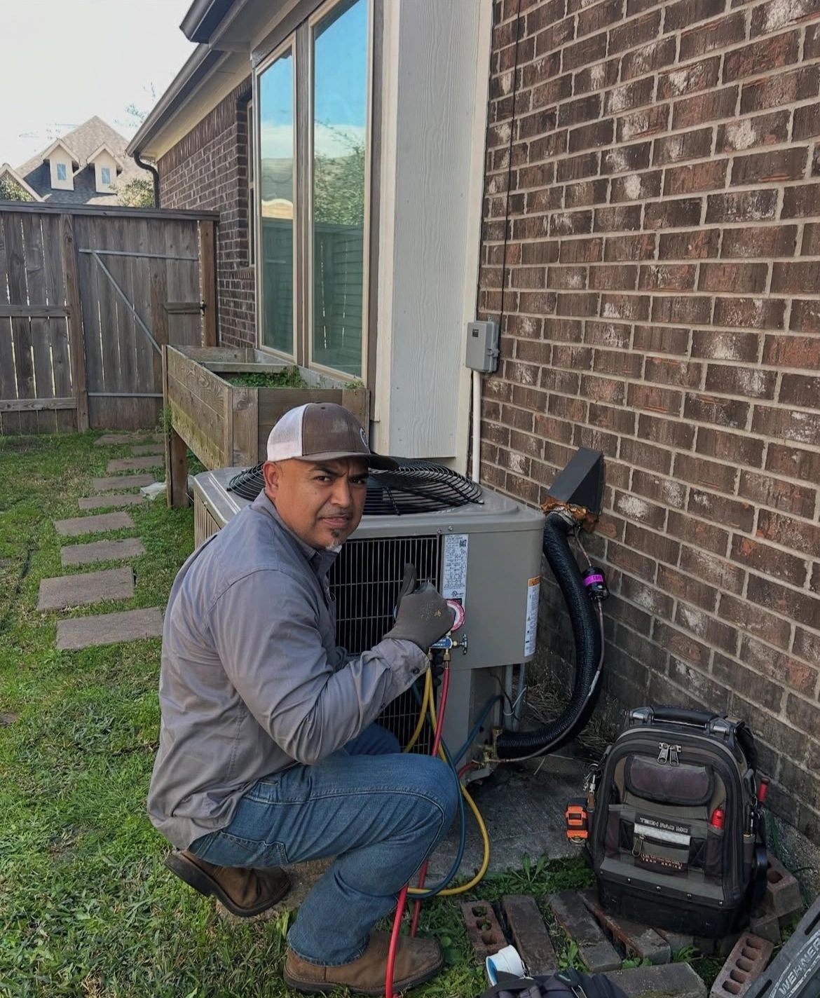 Strong Village technician servicing a residential outdoor air-conditioning unit